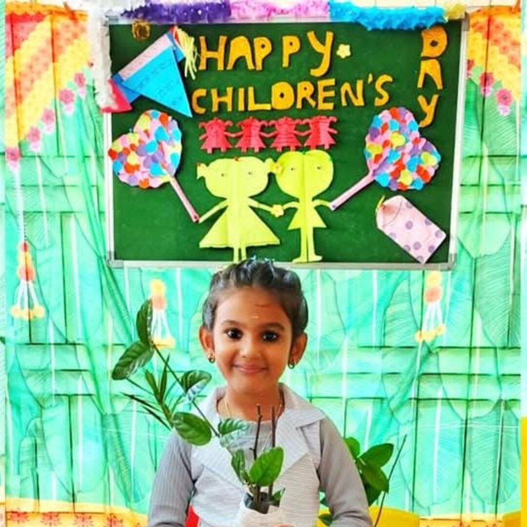 A Smiling Rainbows student holding a sapling during a Children's Day celebration